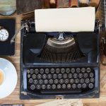Vintage typewriter surrounded by books and office supplies